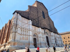 In der Julihitze empfängt Bologna die Reisenden mit engen Gassen, endlosen Arkaden und dem Duft von Kaffee aus jeder Bar. Und dann, auf der Piazza Maggiore, erhebt sich plötzlich ein riesiges Bauwerk – die Basilika San Petronio, die größte Kirche Bolognas und ein wahrer Riese, der bis heute unvollendet geblieben ist. Die Fassade erzählt eine eigene Geschichte Ihre Fassade erzählt eine eigene Geschichte: Der untere Teil glänzt mit weißem Marmor und Mustern, während der obere roh aus Ziegeln besteht. Sie wirkt dadurch ein wenig unvollständig – doch genau das macht ihren besonderen Charme aus. Es ist, als würde man ein Stück lebendige Geschichte sehen, halb vollendet, halb Traum. Der Bau begann bereits 1390. Die Bologneser wollten eine Kirche errichten, die sogar den Petersdom in Rom übertreffen sollte. Fast hätten sie es geschafft – San Petronio gehört zu den zehn größten Kirchen der Welt. Doch der Papst bemerkte schnell den Ehrgeiz der Stadt und stoppte die gewaltigen Pläne: „Rom ist das Zentrum, Bologna soll zweitrangig bleiben.“ So blieb sie: großartig, aber unvollendet. Kleiderordnung in der Basilika muss beachtet werden Im Inneren empfängt einen kühle Weite. Hohe Gewölbe, bunte Glasfenster, das Licht, das von oben fällt – und das Gefühl, dass hier immer Platz für Stille bleibt. In der Kirche gibt es viele Kunstschätze, doch am meisten erstaunt die Meridianlinie – ein schmaler Messingstreifen, der in den Boden eingelassen ist. Durch ein kleines Loch in der Decke markiert die Sonne täglich die Zeit und die Jahreszeit. Im 17. Jahrhundert war dies eine Art astronomisches Observatorium! Wir traten ein, während draußen die Hitze drückte. Am Eingang kontrollieren Helfer die Kleidung: Hier gelten, wie in den meisten großen Kirchen Italiens, Regeln der Anständigkeit. Wer Shorts oder Röcke trägt, die zu kurz sind, bekommt leichte Schals zum Bedecken. Sie sind durchsichtig, aber ausreichend – und so sehen plötzlich alle Touristen ein wenig gleich aus, als gehörten sie zu einem Klub von Reisenden auf der Suche nach Kühle und Schönheit. Pause auf den Treppen der Basilika Drinnen erlebten wir eine Messe auf Polnisch. Die Stimmen des Chors hallten unter den gotischen Gewölben wider, und es war eigenartig und schön, eine vertraute slawische Sprache im Herzen einer italienischen Stadt zu hören. Der schönste Moment kam, als wir hinausgingen. Die Hitze schlug uns ins Gesicht, und wie viele andere setzten wir uns auf die breiten Stufen vor der Basilika. Hier ruht immer jemand: Touristen mit Rucksäcken, Einheimische mit Eis, Studenten mit Gitarren. Ein wenig Schatten – und man spürt, dass man im Rhythmus der Stadt mitschwingt. Geschichte und Gegenwart fließen zusammen San Petronio ist nicht nur ein architektonisches Denkmal. Sie ist ein Symbol dafür, wie Bologna immer nach mehr strebte, als man ihr zugestand. Ein Ort, an dem Geschichte und Gegenwart zusammenfließen: der alte Traum von Größe, Gebete in vielen Sprachen, Lieder auf dem Platz und der lebendige Puls der Stadt. Anreise zur Basilika San Petronio 📍 Adresse: Piazza Maggiore, Bologna, Italien. 🚆 Vom Bahnhof Bologna Centrale: Zu Fuß sind es etwa 20 Minuten. Am einfachsten geht man die Via dell’Indipendenza entlang – die Hauptstraße, die direkt ins Zentrum führt. 🚌 Wer nicht laufen möchte, kann auch den Bus nehmen (z. B. Nr. 25, 27 oder 30). Aussteigen sollte man an der Haltestelle Rizzoli, die nur wenige Schritte vom Platz entfernt liegt. 🚶‍♀️ Befindet man sich bereits im Zentrum von Bologna, kann man sie unmöglich übersehen: Die Basilika beherrscht die gesamte Piazza.