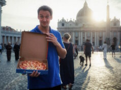 Von allen Sünden befreit: Ein Domino’s Mitarbeiter präsentiert die „Waikiki“ mit Ananas auf dem Petersplatz vor dem Petersdom – Teil der Aktion „Pardoned Pineapple Pizza“, mit der Domino’s augenzwinkernd um Vergebung für die vermeintliche Pizzasünde bittet. (Foto: © Domino's)