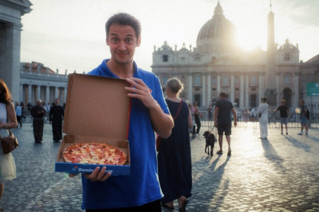 Von allen Sünden befreit: Ein Domino’s Mitarbeiter präsentiert die „Waikiki“ mit Ananas auf dem Petersplatz vor dem Petersdom – Teil der Aktion „Pardoned Pineapple Pizza“, mit der Domino’s augenzwinkernd um Vergebung für die vermeintliche Pizzasünde bittet. (Foto: © Domino's)