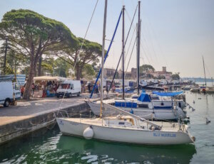 Markttag in Lazise: Zwischen Yachthafen, alten Bäumen und bunten Ständen genießen Urlauber am Gardasee italienisches Flair und regionale Spezialitäten. (Foto: © Lago di Garda Camping)