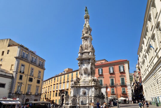 Leben in italienischen Großstädten, hier Neapel: Im Herzen der Altstadt prägt die imposante Guglia dell’Immacolata das lebendige Stadtbild, ein typischer Treffpunkt zwischen Alltag, Geschichte und mediterranem Leben. (Foto: © Bastian Glumm)