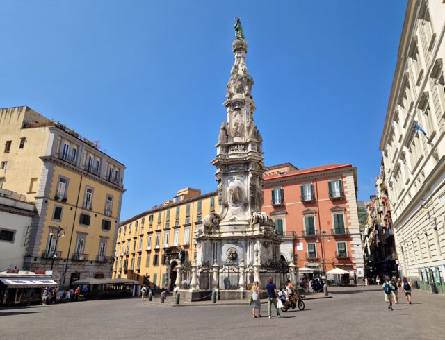 Leben in italienischen Großstädten, hier Neapel: Im Herzen der Altstadt prägt die imposante Guglia dell’Immacolata das lebendige Stadtbild, ein typischer Treffpunkt zwischen Alltag, Geschichte und mediterranem Leben. (Foto: © Bastian Glumm)
