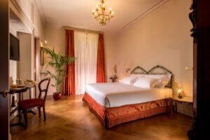 Einblick in eines der stilvoll eingerichteten Zimmer des Hotel Locarno – mit antiken Möbeln, Parkettboden und elegantem Lichtkonzept. (Foto: © Hotel Locarno)