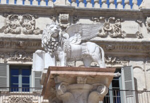 Auf der Westseite der Piazza, vor dem barocken Palazzo Maffei, steht der venezianische Löwe des heiligen Markus – mächtig und schweigsam, mit einem geöffneten Buch in den Pranken. (Foto: © Bastian Glumm)