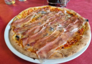 Pizza in Südtirol mit regionalem Speck. Ein Beispiel dafür, wie lokale Zutaten Italiens kulinarische Vielfalt prägen, die nun als UNESCO-Kulturerbe anerkannt wurde. (Foto: © Bastian Glumm)