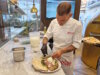 Finaler Handgriff an der Nuda e Cruda: Der vorgebackene Pizzateig wird im Anticus mit frischen Zutaten wie Büffelmozzarella, Rucola und Prosciutto belegt – ein kreatives Gericht zwischen Pizza und gefüllter Focaccia. (Foto: © Bastian Glumm)