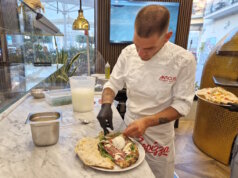 Finaler Handgriff an der Nuda e Cruda: Der vorgebackene Pizzateig wird im Anticus mit frischen Zutaten wie Büffelmozzarella, Rucola und Prosciutto belegt – ein kreatives Gericht zwischen Pizza und gefüllter Focaccia. (Foto: © Bastian Glumm)