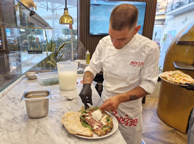 ristorante-anticus-pizzeria-pozzuoli (4) Finaler Handgriff an der Nuda e Cruda: Der vorgebackene Pizzateig wird im Anticus mit frischen Zutaten wie Büffelmozzarella, Rucola und Prosciutto belegt – ein kreatives Gericht zwischen Pizza und gefüllter Focaccia. (Foto: © Bastian Glumm)