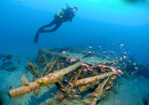 Taucher über dem Flügel einer Ju 52 vor Punta di Fetovaia auf Elba: Das Wrackfragment liegt auf über 40 Metern Tiefe und ist Ziel eines anspruchsvollen Tiefentauchgangs. (Foto: © "Spiro Sub Diving - Elba")
